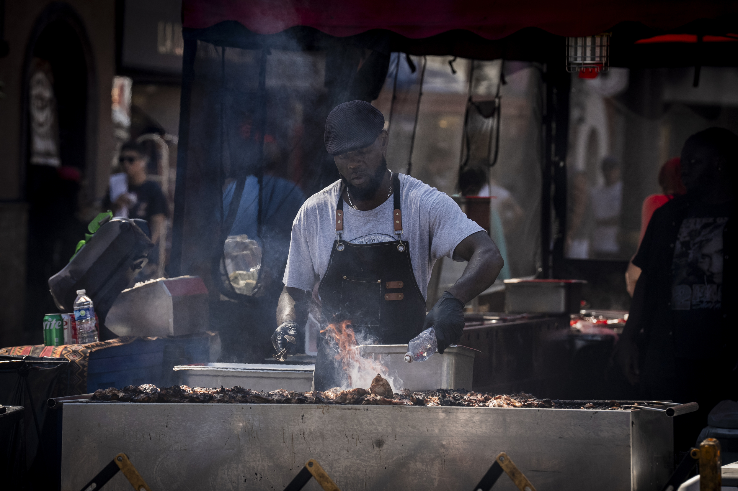A street fair vendor grilling barbecue over an open flame, wearing a leather apron and surrounded by smoky ambiance.